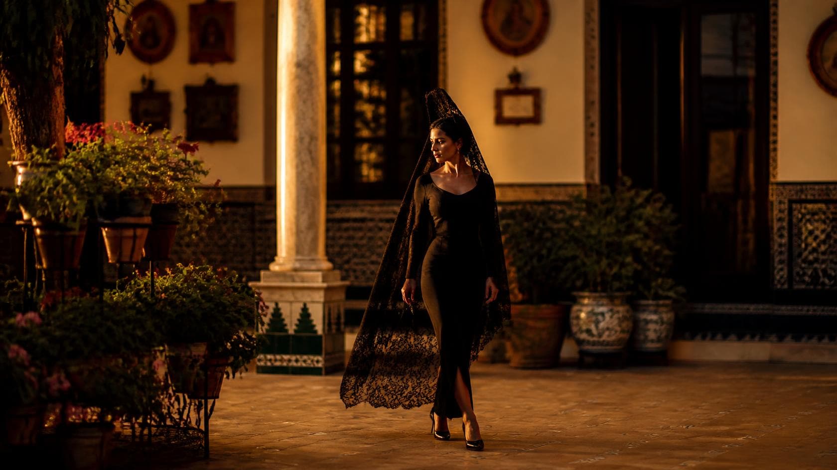 Mujer con mantilla y peineta en un patio andaluz al atardecer